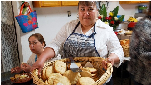 Doña Esthela delivers fresh-baked pan de elote to the kitchen.