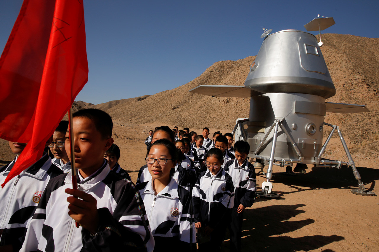 Un grupo de estudiantes escolares junto al prototipo de una cápsula espacial.